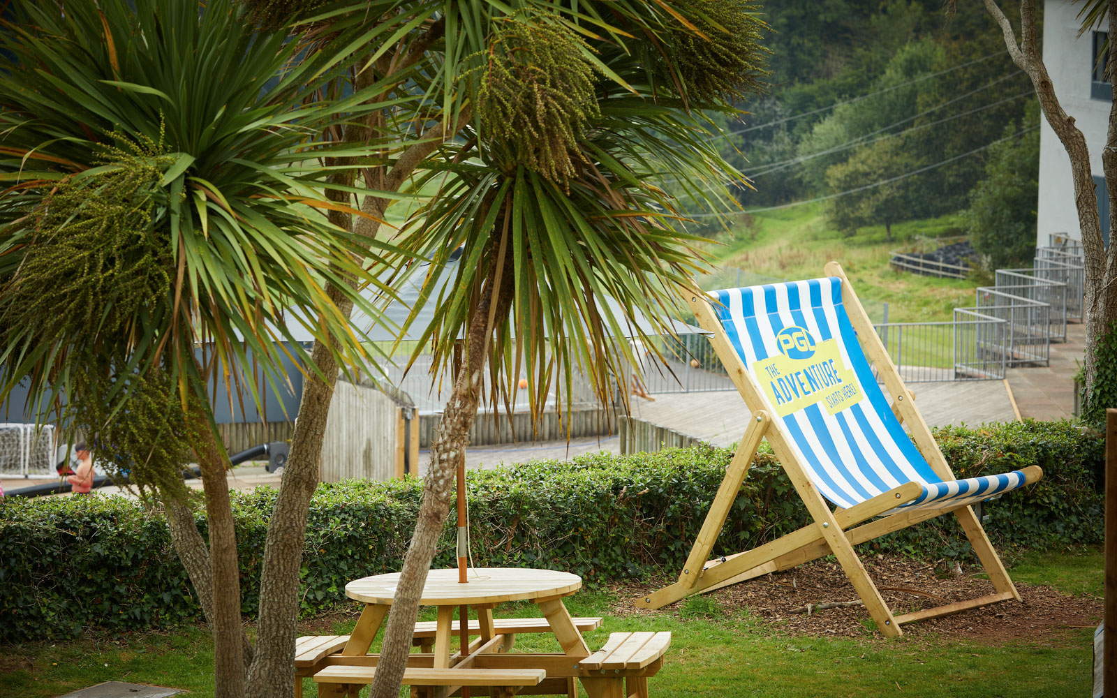 Relaxation area at PGL Barton Hall with deck chair, palm trees and picnic table