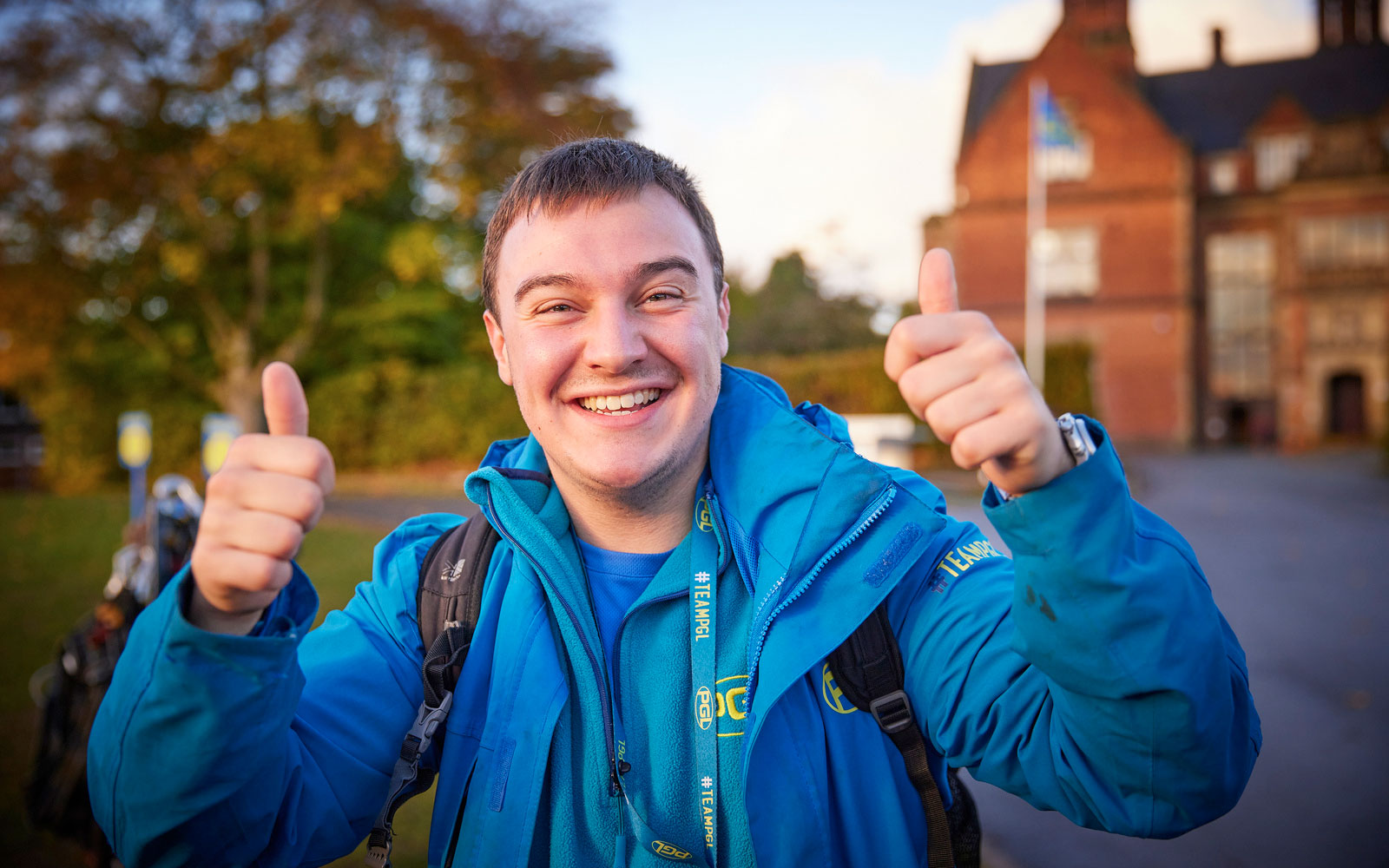 A PGL employee giving a double thumbs up in front of the mansion at PGL Boreatton Park.